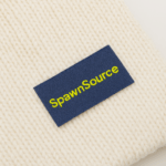 Off white beanie with a SpawnSource™ woven label sewn on it